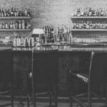 sante-84_edited - Edible NEW Bar interior with shelves of liquor bottles behind a counter and glassware in front.